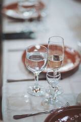 Elegant dining setup featuring sparkling wine and water glasses at a festive table under warm lights