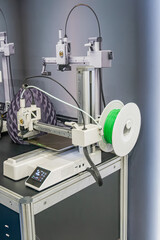Industrial precision machine tool with gantry structure, engaged in cutting or engraving on a flat metalmaterial surface Gantry has two circular tools one greenish, control panel with buttons and