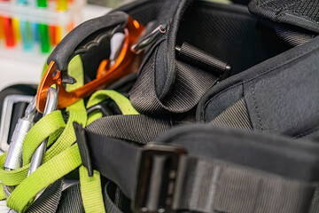 Black backpack containing mountaineering gear, including orange safety goggles and a dark electronic device, located in an indoor setting with multiple straps and compartments