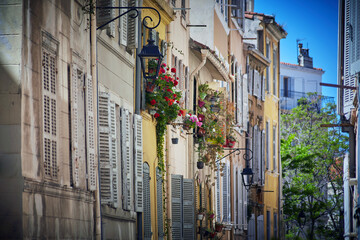 Vintage Marseille street with colorful shuttered windows and flower pots in historic Le Panier district on sunny day
