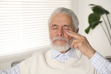 Senior man suffering from eyestrain at home
