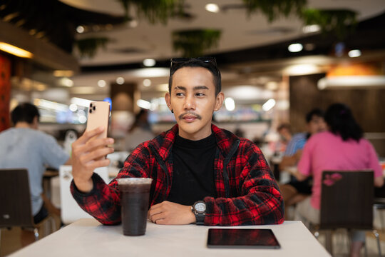 Portrait of nonbinary genderfluid young Asian gay man using phone