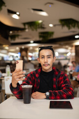 Portrait of nonbinary genderfluid young Asian gay man using phone