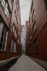 low and wide angle view of a narrow walk way between two red bricks buildings