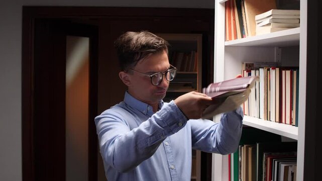 man shakes out hidden money from a book. Savings in a book in a library.