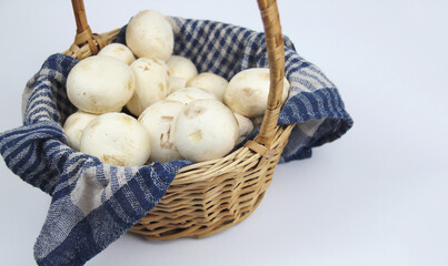 Champignon mushrooms in a basket on a white background
