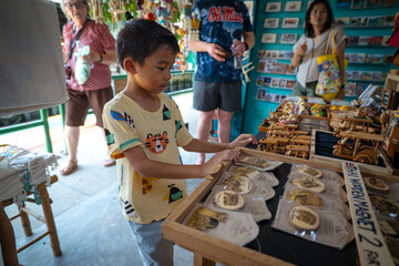 Kid enjoy buy handmade toy in souvenir shop floating market