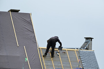 ouvrier couvreur sur un toit d'habiation en cours de rénovation