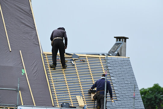 ouvrier couvreur sur un toit d'habiation en cours de r&eacute;novation