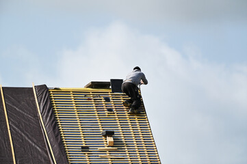 ouvrier couvreur sur un toit d'habiation en cours de rénovation