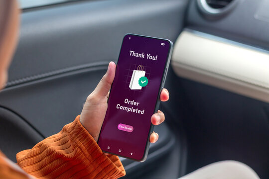 Woman holding smartphone displaying order completed notification. Online shopping concept.