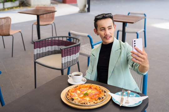 Portrait of nonbinary genderfluid young Asian gay man eating pizza in restaurant