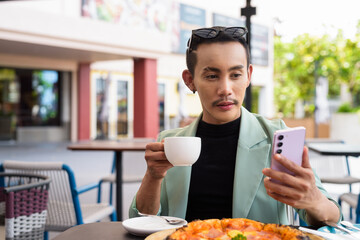 Portrait of nonbinary genderfluid young Asian gay man eating pizza ourdoors