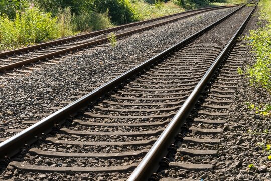 Parallel railroad tracks stretching into the distance on sunny day