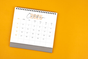 Top view of October 2025 desk calendar on yellow color background.