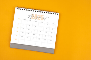 Top view of August 2025 desk calendar on yellow color background.