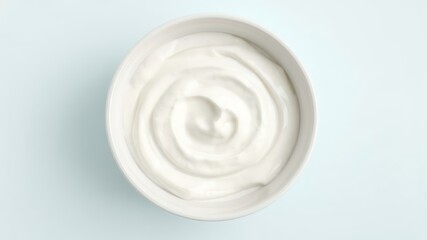 Creamy white dairy treat swirled smoothly in a simple white bowl, presented on a clean, light pastel background