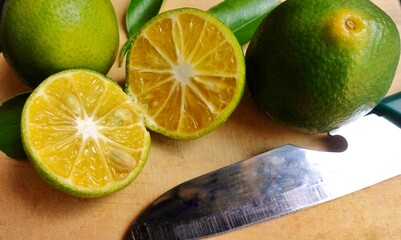 Whole and sliced ​​fresh oranges on a cutting board in the kitchen.