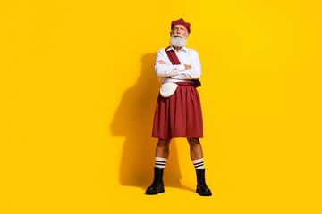Mature man in traditional Scottish attire with yellow background showcasing cultural elegance in a cheerful pose