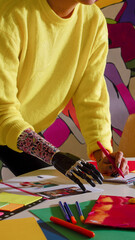 Modern artist sketching with prosthetic hand in vibrant studio full of creative materials
