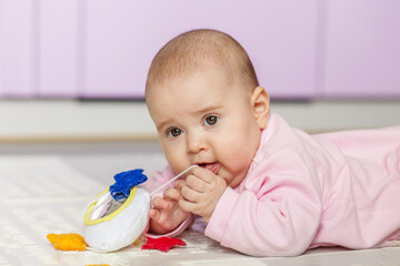 Baby chewing on soft toy string indoors. Copy space