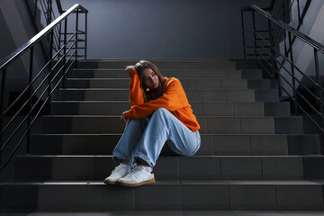 Bullying. Upset teenage girl on stairs indoors