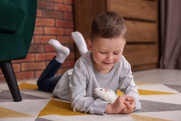Little boy with his pet rat on floor at home