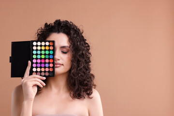 Woman covering eye with eyeshadow palette on beige background. Space for text