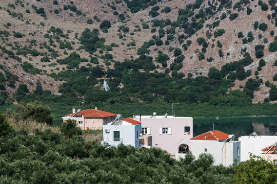 Helicopter releasing water over Lake Kournas after collection to put out the fire