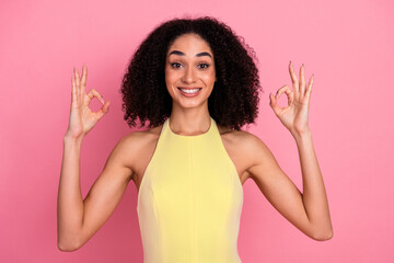 Charming young woman in yellow dress on pink background radiating happiness, style, and positivity...