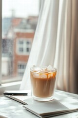 Iced Coffee on Marble Table With Notebook and Pen Next to Window
