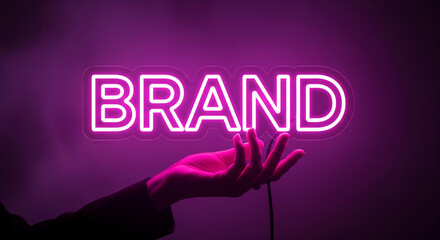 Pink neon "BRAND" sign held in hand against purple background, showcasing branding, identity, and marketing concepts