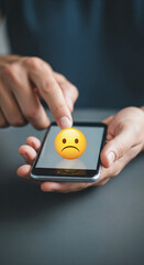 Close-up of hands holding smartphone displaying unhappy emoticon, symbolizing negative feedback or dissatisfaction, showcasing digital communication issues