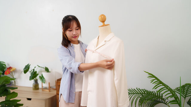 Asian young woman designing clothing measuring mannequin shirt design process in studio fashion designer creative dressmaker tailoring - Powered by Adobe