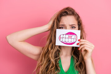 Attractive Young Woman Holding a Drawing of Teeth Against a Pink Background, Expressing Thoughts on...