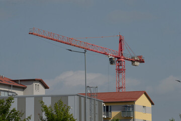 A large red crane is currently positioned in front of a building that is actively undergoing the construction process at this time