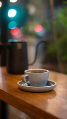 Cup of hot coffee or tea and teapot on wooden table with bokeh background