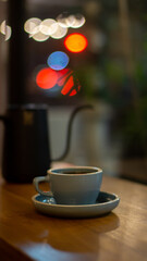 A cup of hot coffee or tea and teapot on wooden table with bokeh background	
