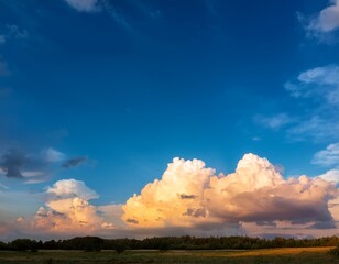 Obraz premium vivid blue sky with large fluffy white clouds illuminated by soft golden sunlight creating a peaceful and uplifting atmosphere