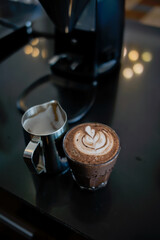 A glass of hot latte with froth art on café counter