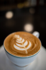 Close up of a cup of coffee latte with froth art on the table	