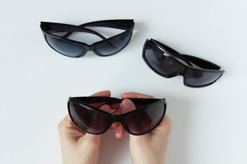 Black framed sunglasses in the hands of a Caucasian woman. The buyer chooses glasses.