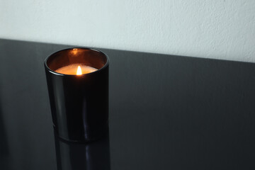 luxury aromatic scented candle glass is on black glass table with a few rocks and background of...