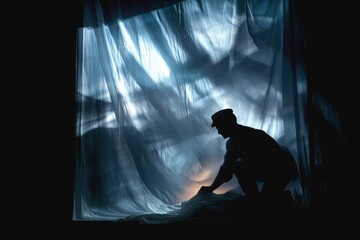 Performer prepares stage with fabric backdrop during dramatic lighting design before a theatrical production