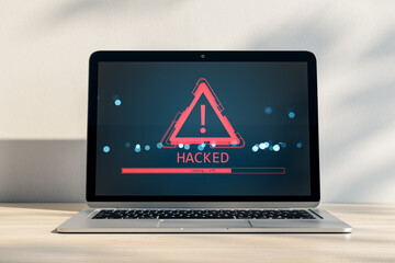Cybersecurity alert with hacked warning icon and exclamation mark on laptop screen on desk in...