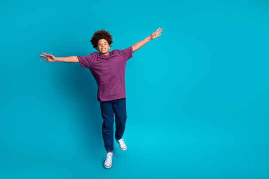 Smiling young boy with curly hair in casual outfit joyfully posing on vibrant blue background expressing happiness - Powered by Adobe