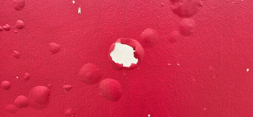 The background of the red painted wall has blistered paint marks. The red painted cement wall has...