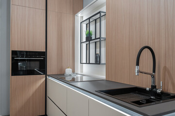 modern  kitchen. built-in kitchen furniture, upper and lower cabinets, built-in appliances. Black faucet and sink. Wooden kitchen. the kitchen is beige and light shades.