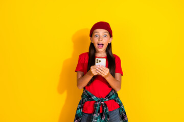 Cheerful girl in casual attire with smartphone expressing excitement and surprise against vibrant...