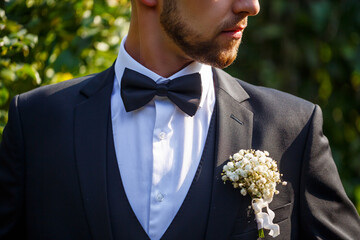 A gentleman in a smart suit and bow tie has a flower in his pocket